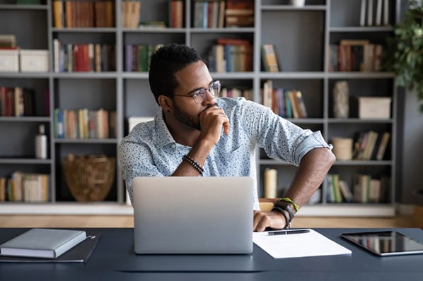 homem sentado a frente do computador pensa sobre sua estratégia de marketing no LinkedIn