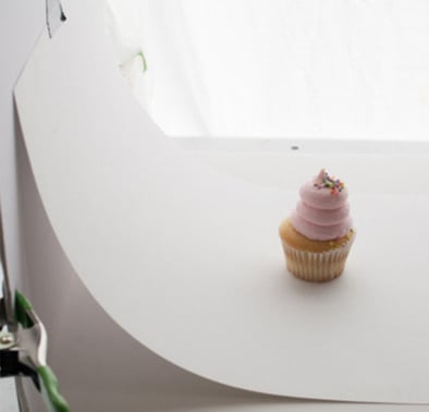 Foto de produto com fundo infinito branco atrás de um cupcake