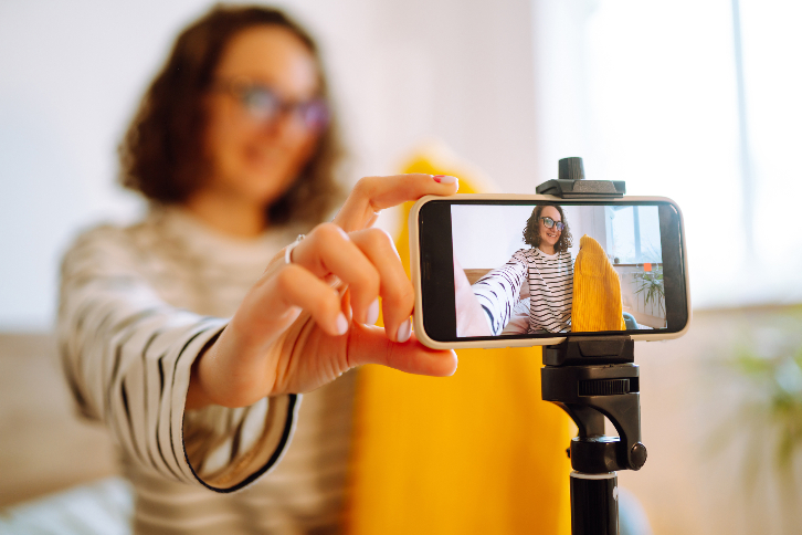 mulher posa para foto com celular, segurando um produto - o planejamento de conteúdo para o Instagram envolve a otimização de imagens 